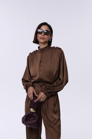 Woman wearing a brown outfit with sunglasses and holding a purple handbag on a white background