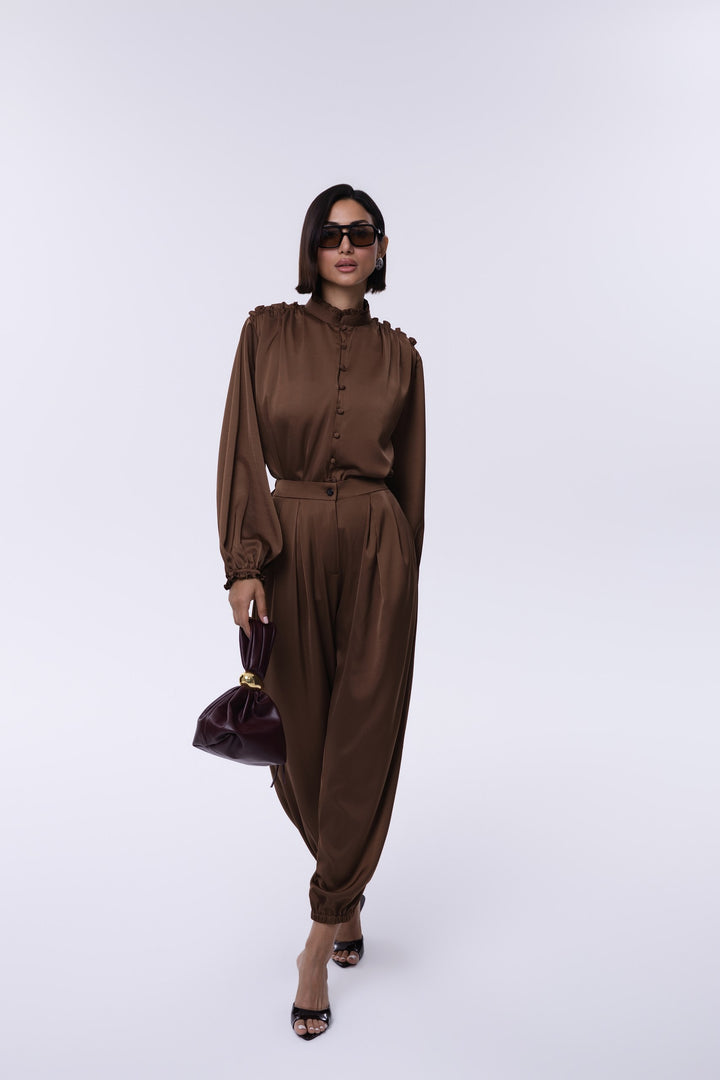 Woman wearing a brown outfit with a matching handbag on a white background