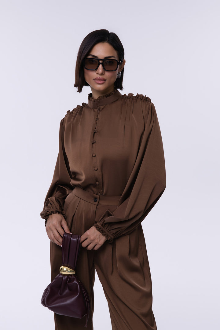 Woman wearing a brown outfit with sunglasses and a purple handbag on a white background