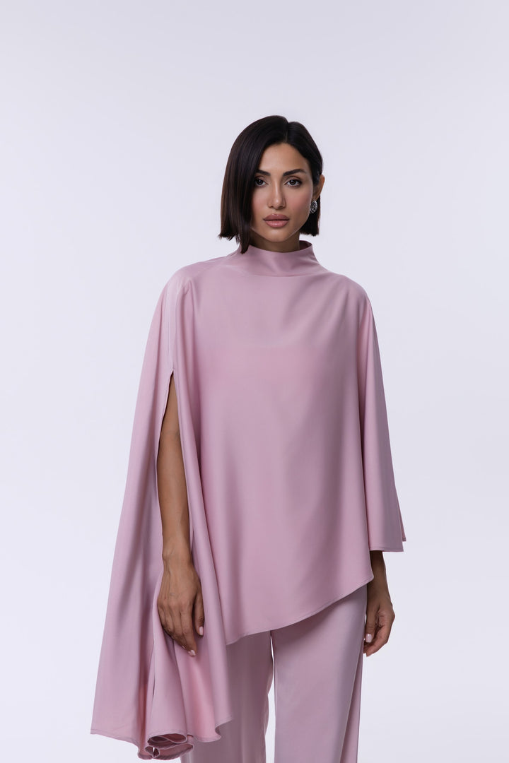 Woman wearing a pink cape over a matching outfit on a white background