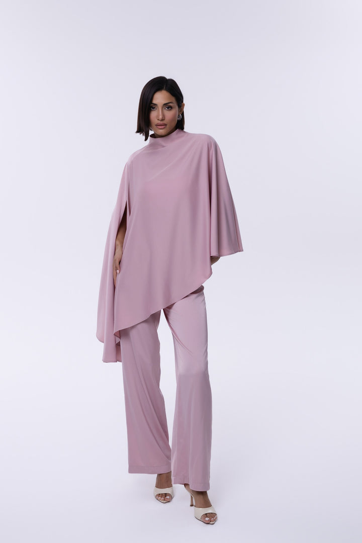 Woman wearing a pink outfit with a cape on a white background