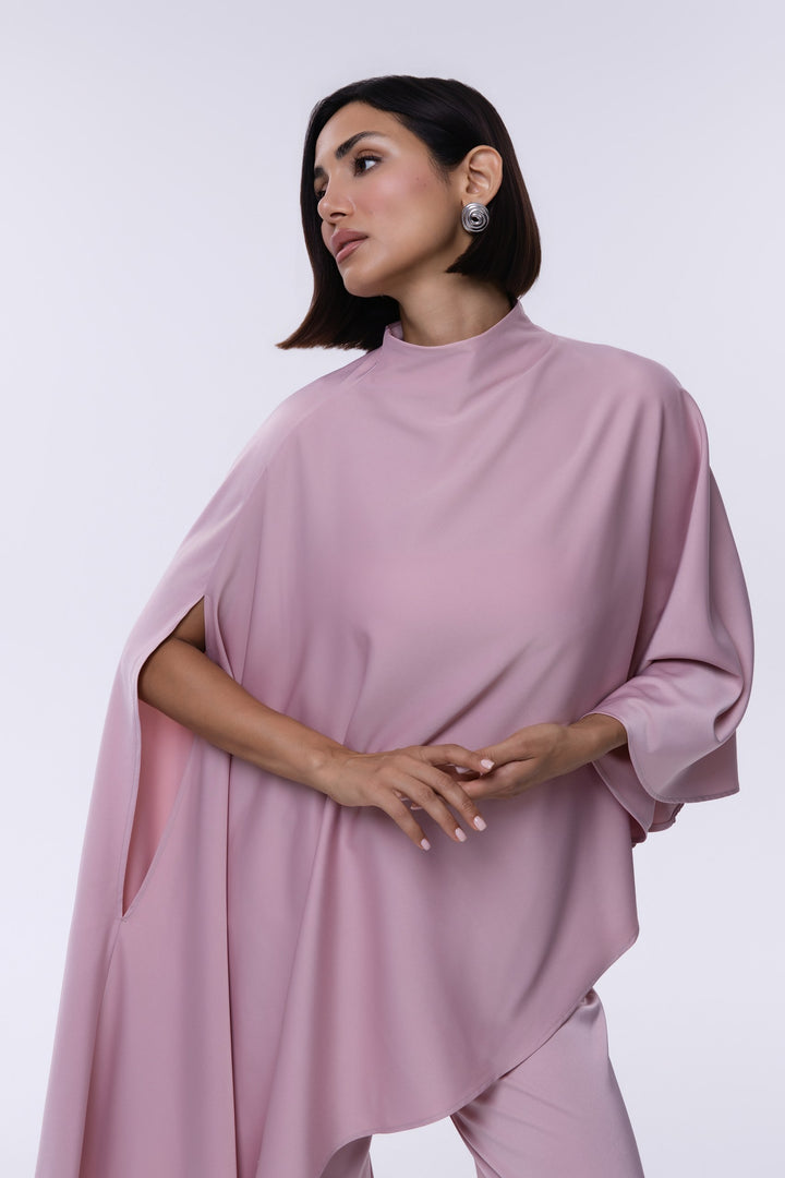 Woman wearing a pink cape over a plain background