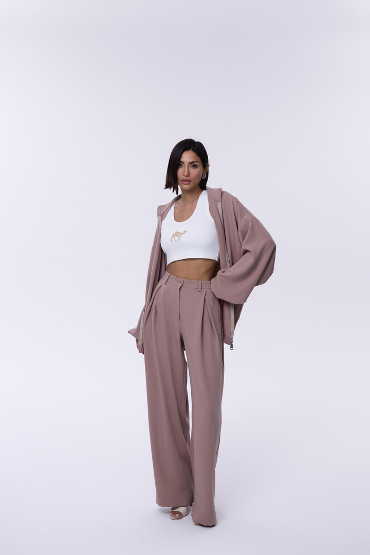Woman wearing a mauve cardigan and pants set with a white top on a white background