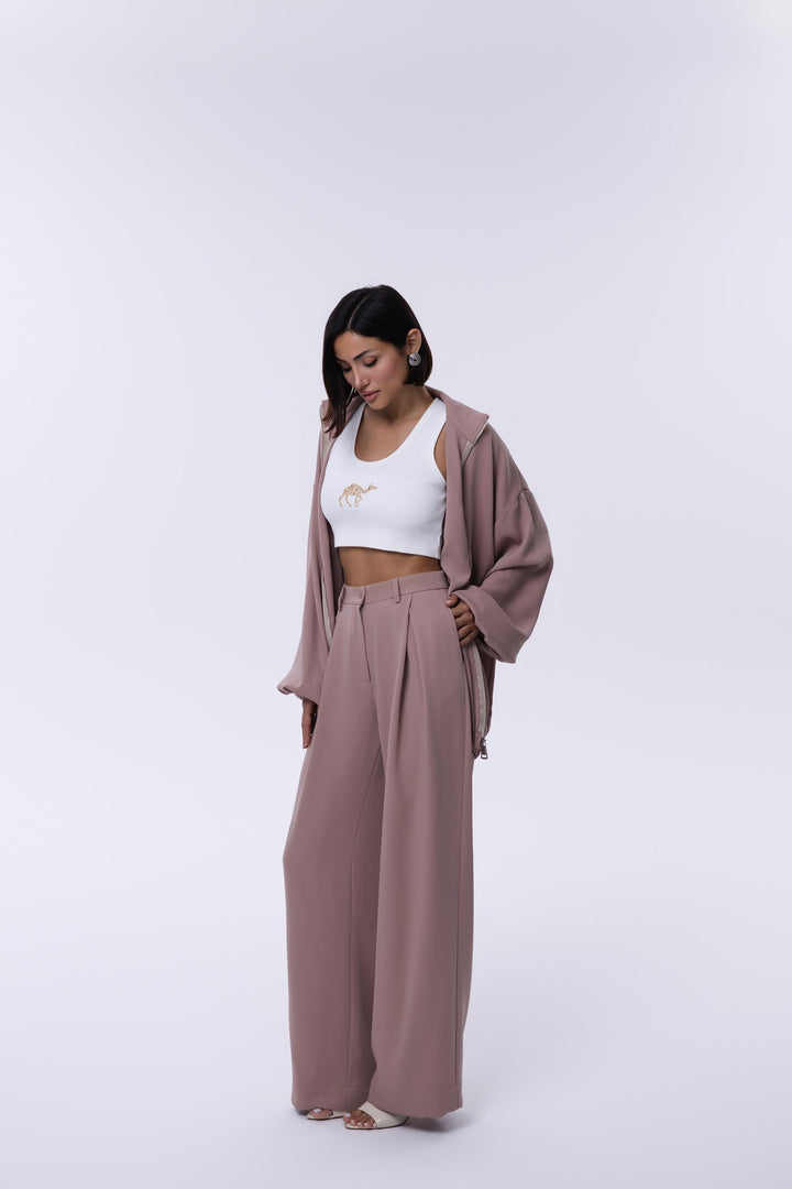 Woman wearing a white crop top and brown wide-leg pants with a matching jacket on a white background