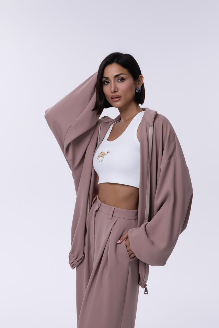 Woman wearing a mauve outfit with a white top on a light gray background