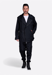 Model wearing a tailored black men’s jacket with asymmetrical zipper and notched lapel, paired with black trousers East Vibe