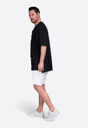 Man wearing white cotton shorts with elastic waistband and side pockets by East Vibe