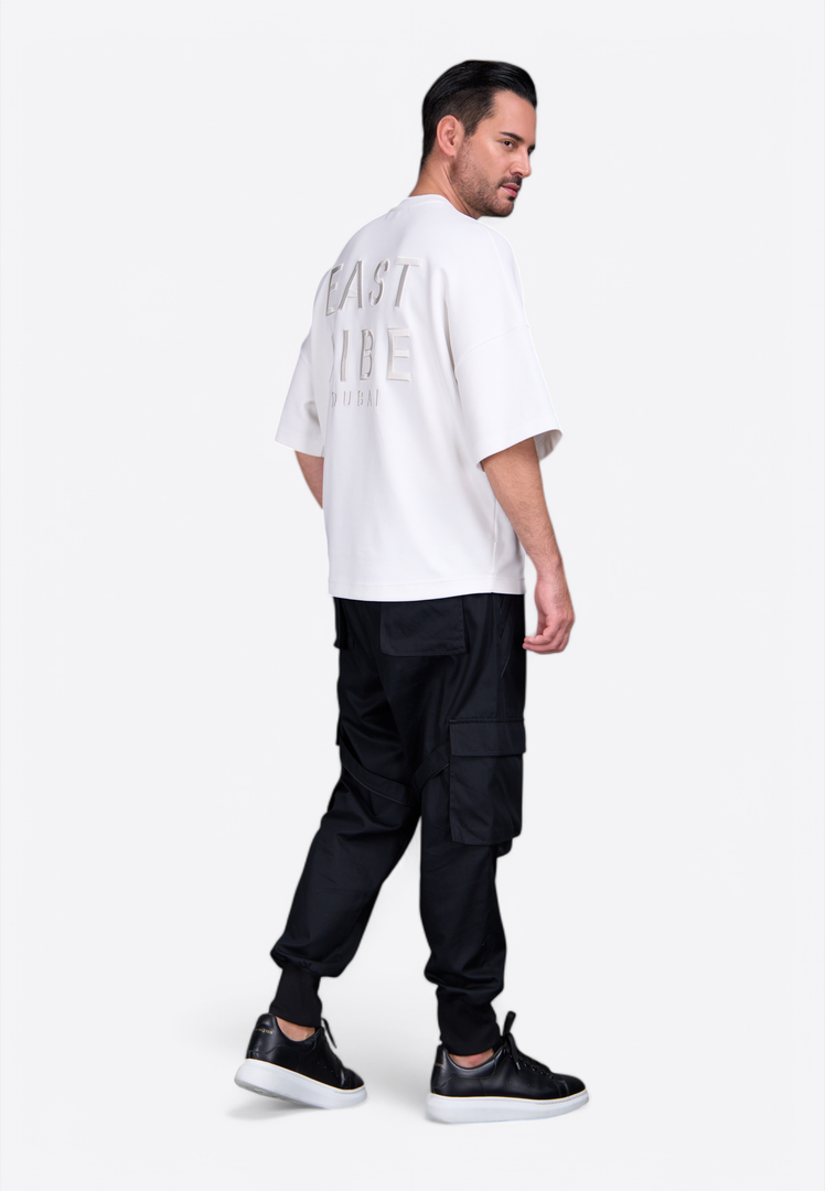 Model wearing white short tassel T-shirt with monogram detail East Vibe