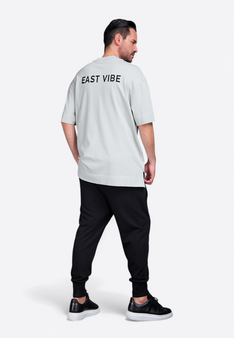 Model wearing men's t-shirt with East Vibe monogram and tassel